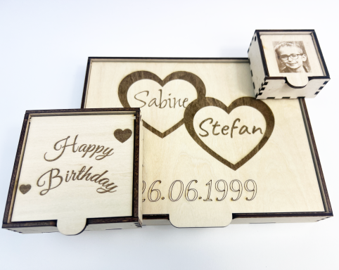 Holzschachteln mit eingravierten Namen und Geburtstag, liebevolles Design.