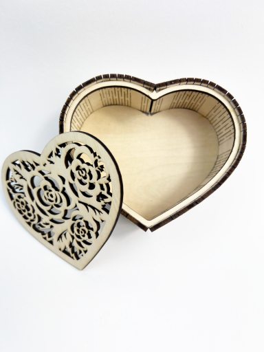 Herzförmige Holzkiste mit aufklappbarem Deckel und floralem Muster.